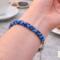 Blue glass bead Kumihimo bracelet worn at a café table, handmade braided bracelet with subtle texture detail